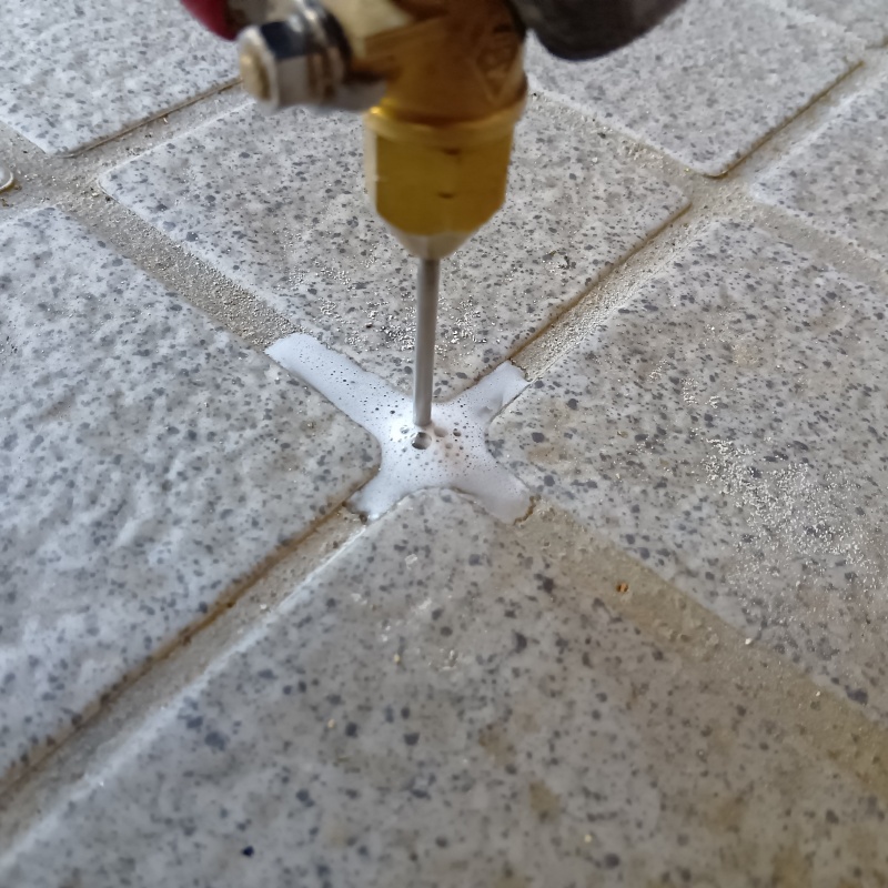 玄関の床にシロアリ駆除剤を注入する様子