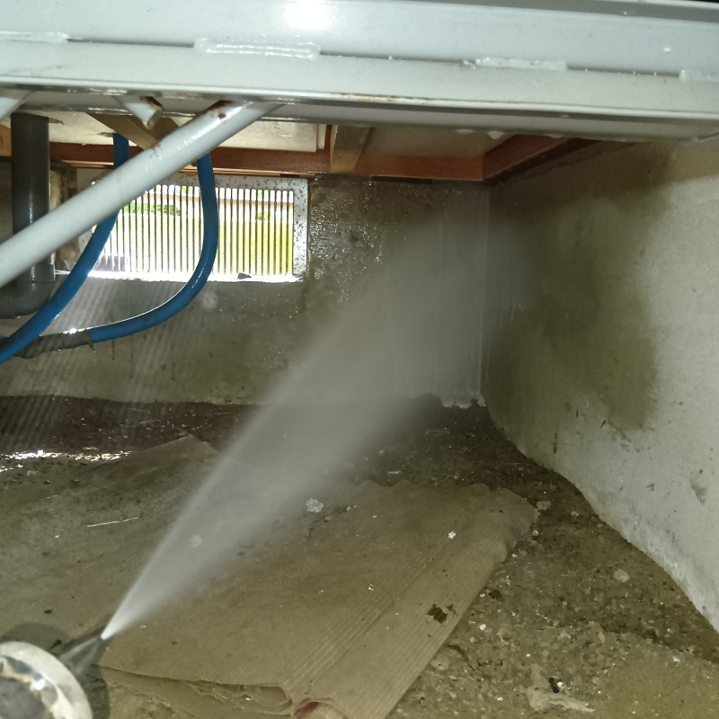 床下の基礎部分にシロアリ駆除剤を散布する様子