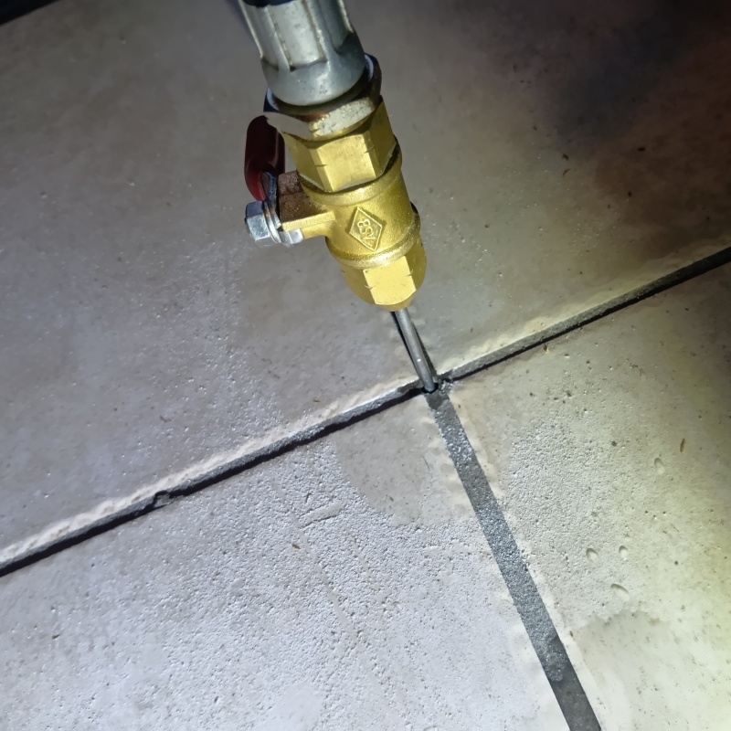 玄関の床にシロアリ駆除剤を注入する様子