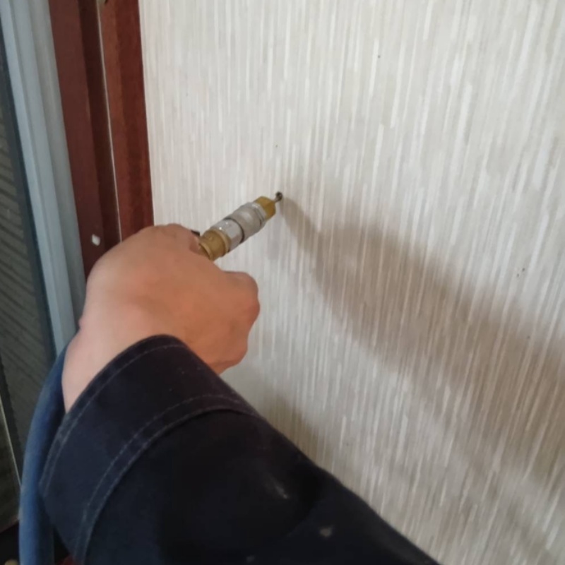 洗面所の壁にシロアリ駆除剤を注入する様子