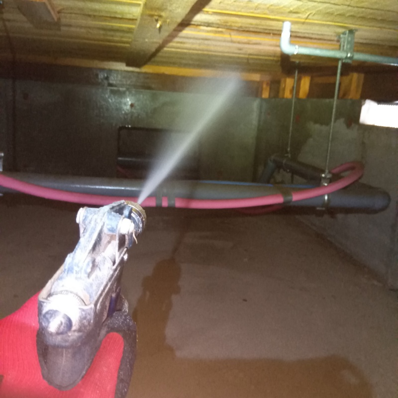 床下木材にシロアリ駆除剤を吹き付ける様子