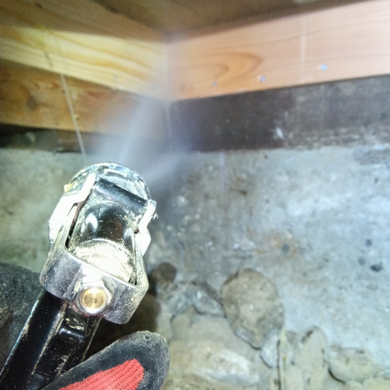 床下木材にシロアリ駆除剤を吹き付ける様子