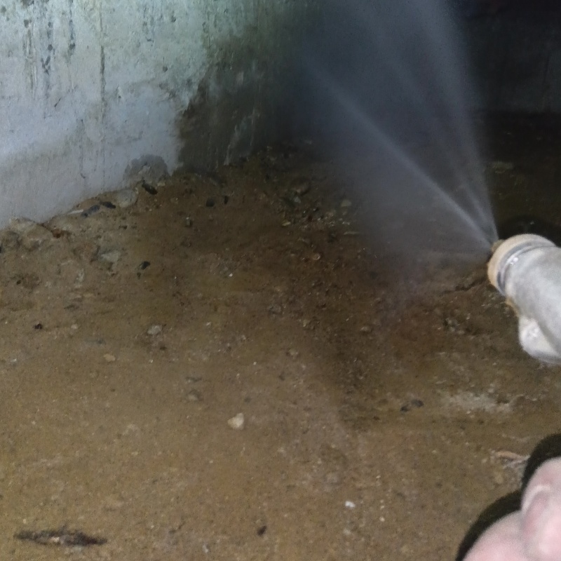 床下の土壌にシロアリ駆除剤を散布する様子