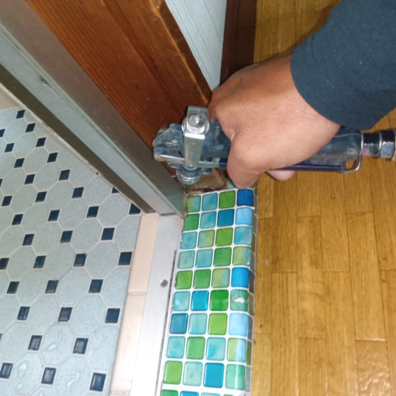 浴室のサッシ部分にシロアリ駆除剤を注入する様子