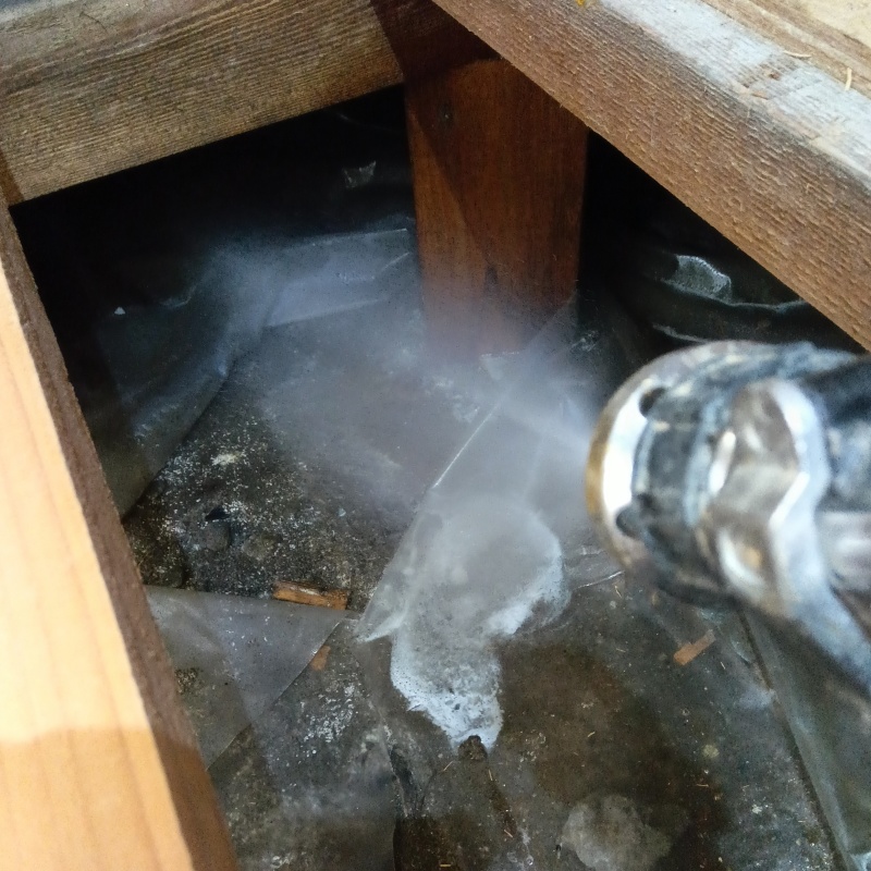 床下の土壌にシロアリ駆除剤を散布する様子