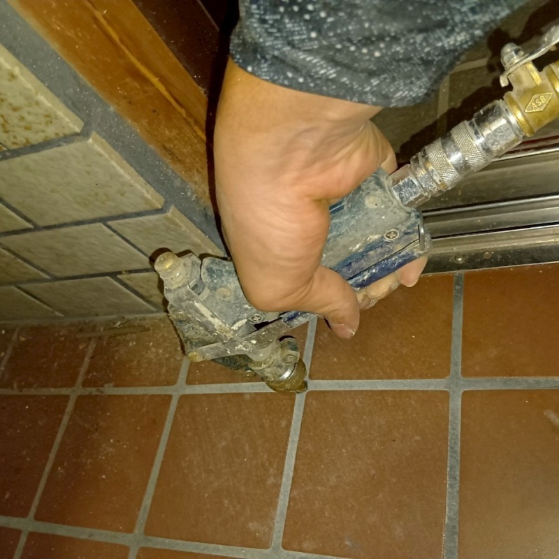 玄関の床にシロアリ駆除剤を注入する様子