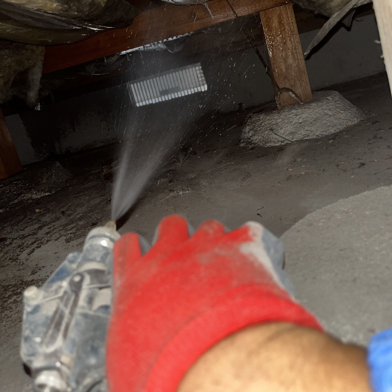 床下の土壌にシロアリ駆除剤を散布する様子