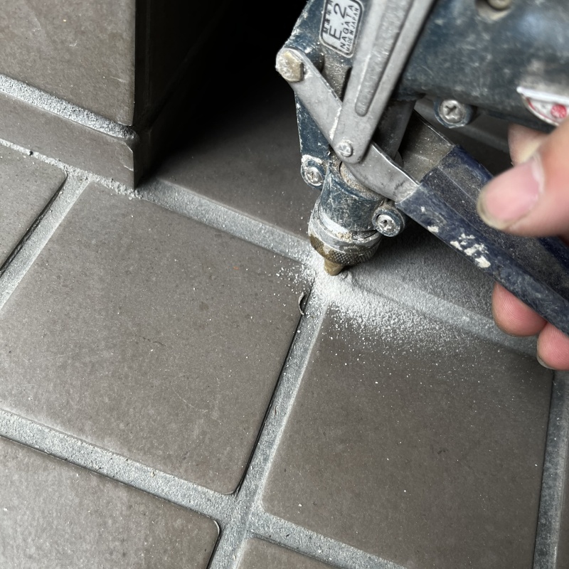 玄関の床にシロアリ駆除剤を注入する様子