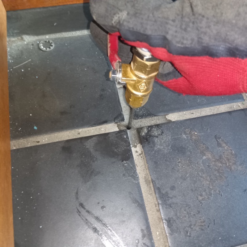 玄関の床にシロアリ駆除剤を注入する様子