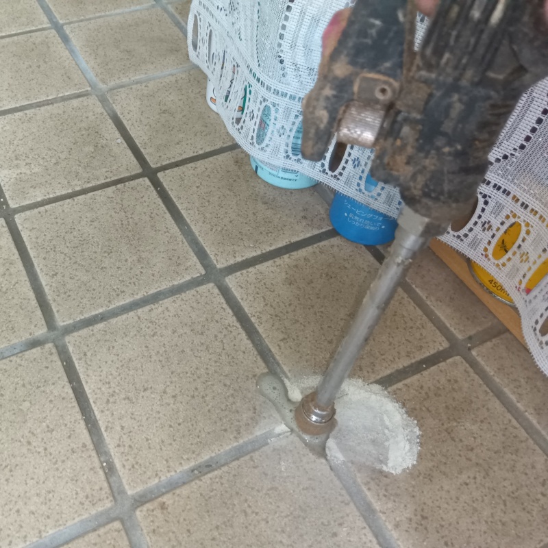 玄関の床にシロアリ駆除剤を注入する様子