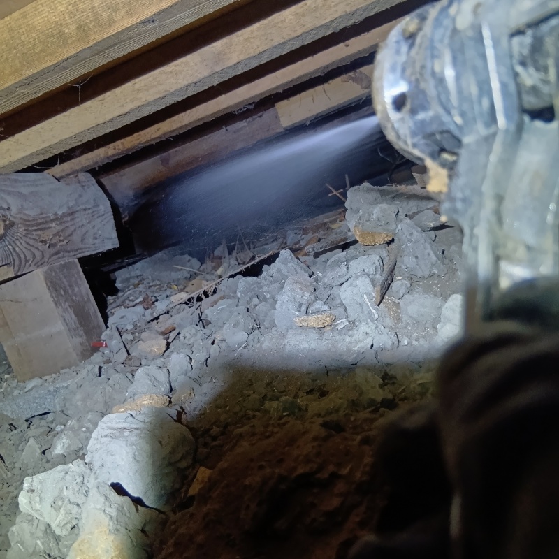 床下の土壌にシロアリ駆除剤を散布する様子