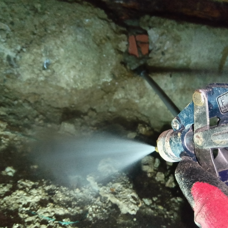 床下の土壌にシロアリ駆除剤を散布する様子