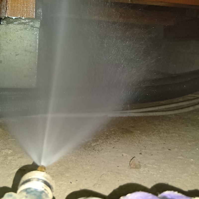 床下の地面にシロアリ駆除剤を散布する様子