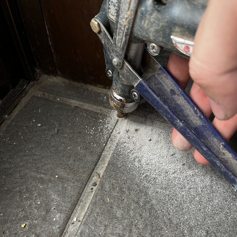 玄関の床にシロアリ駆除剤を注入する様子