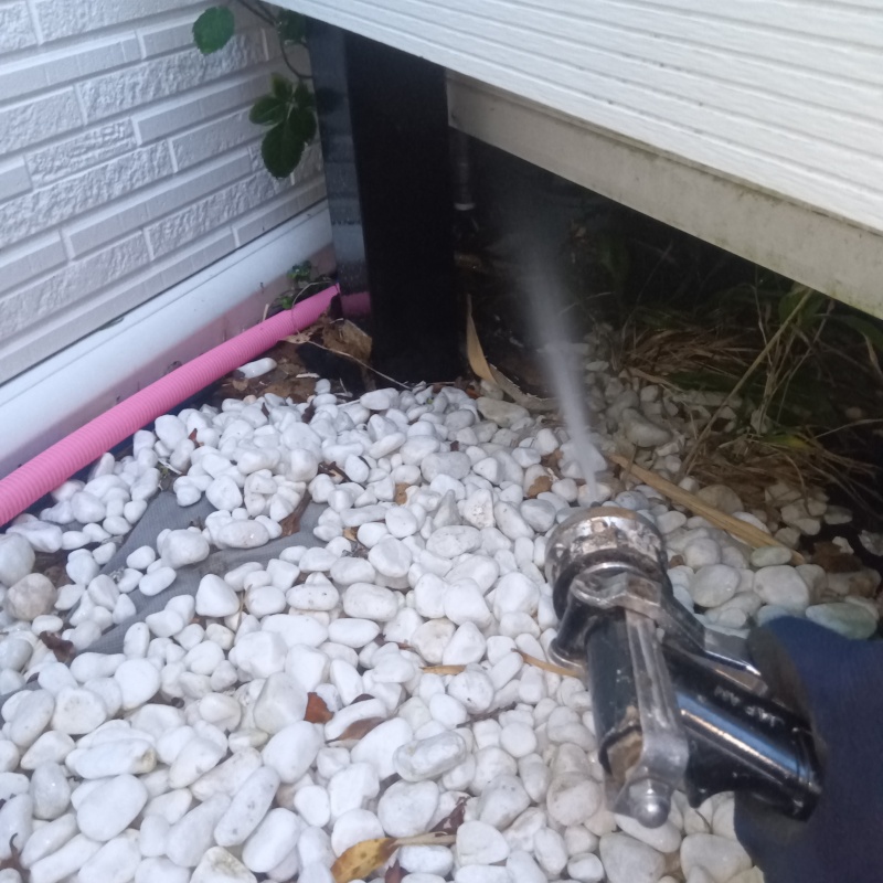 建物の下のすき間からシロアリ駆除剤を散布