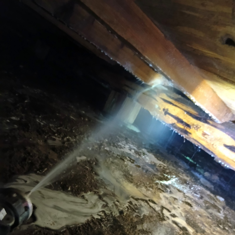 床下木材にシロアリ駆除剤を吹き付けている様子