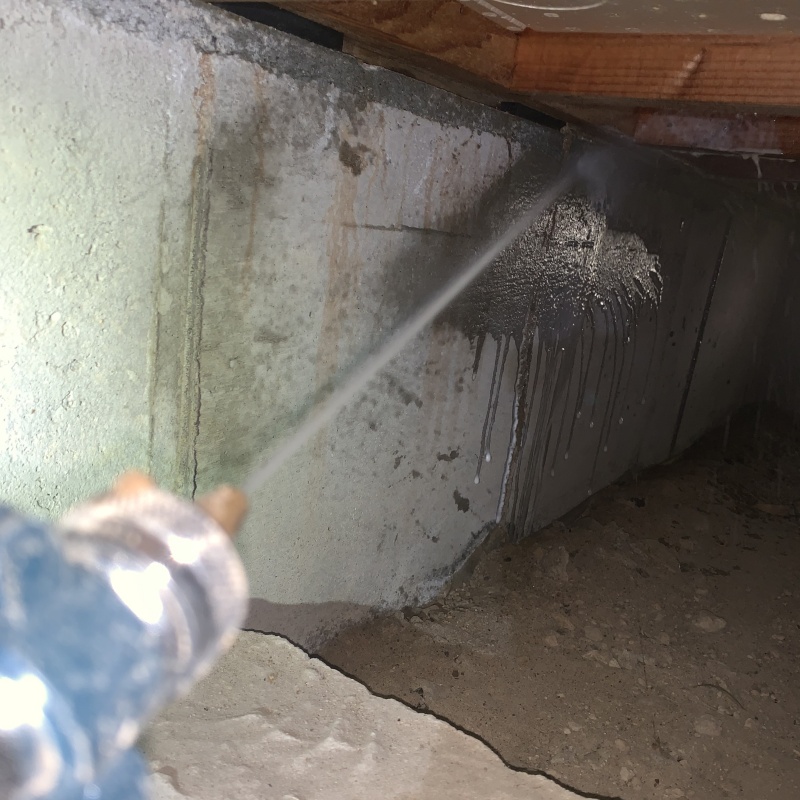 床下の基礎部分にシロアリ駆除剤を散布する様子