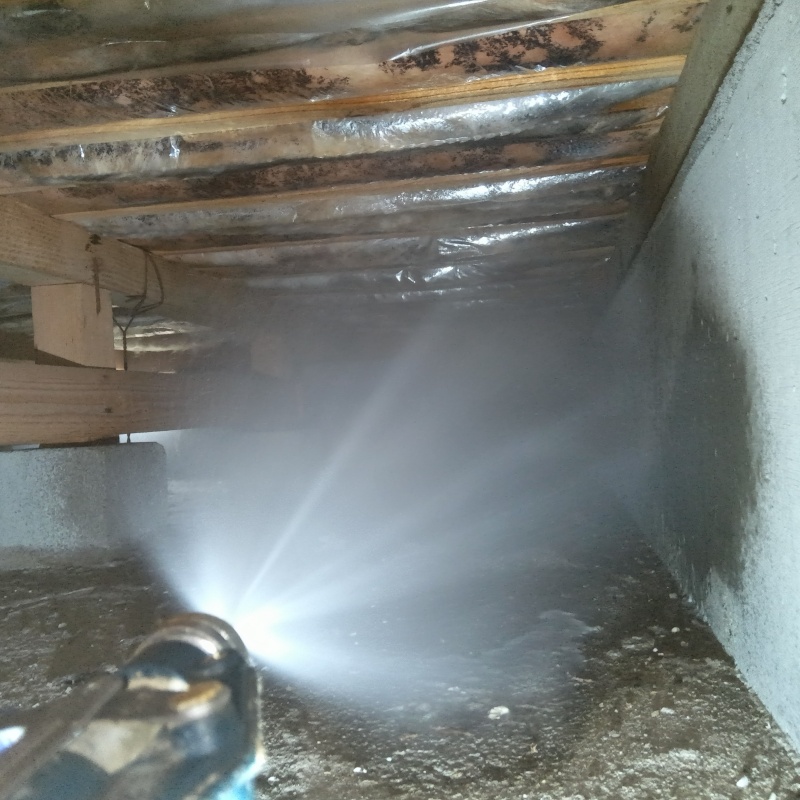 床下の土壌にシロアリ駆除剤を散布する様子