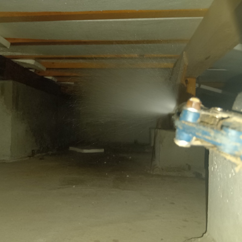 床下の土壌にシロアリ駆除剤を散布する様子