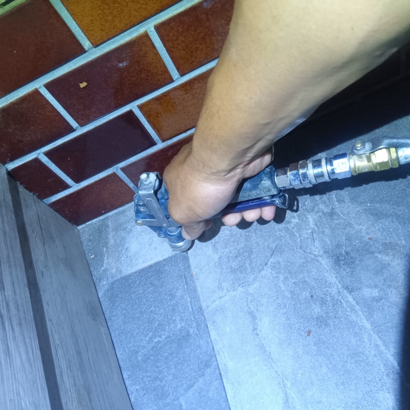 玄関の床にシロアリ駆除剤を注入する様子