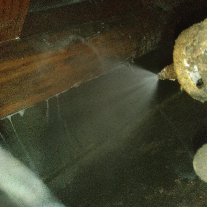 床下木材にシロアリ駆除剤を吹き付ける様子