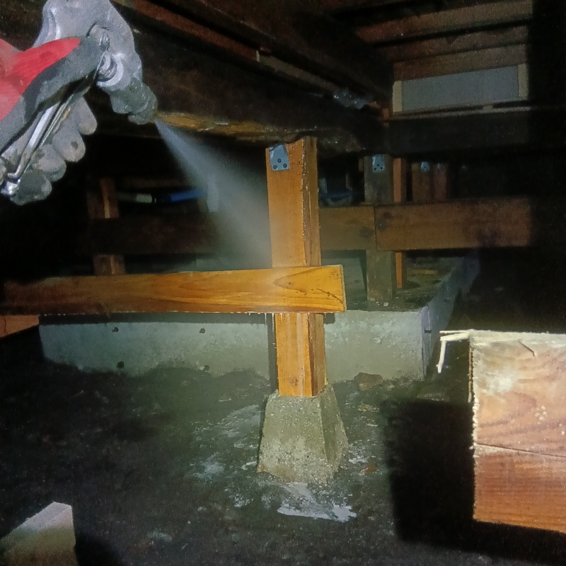 床下木材にシロアリ駆除剤を吹き付ける様子