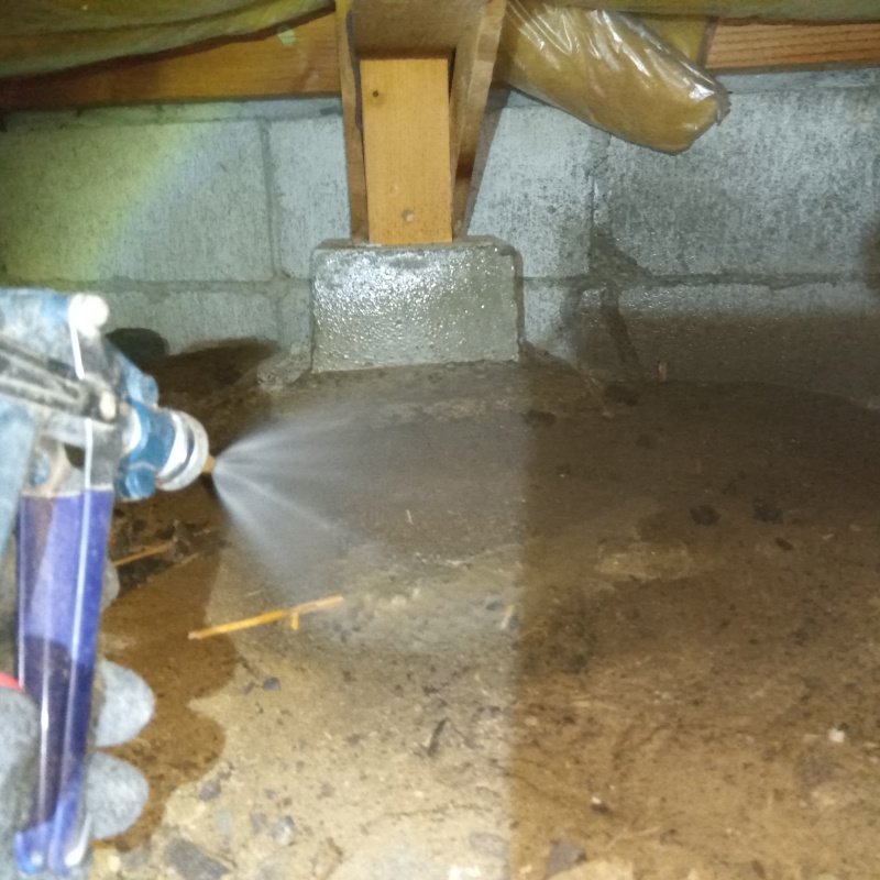 地面にシロアリ駆除剤を吹き付けている様子