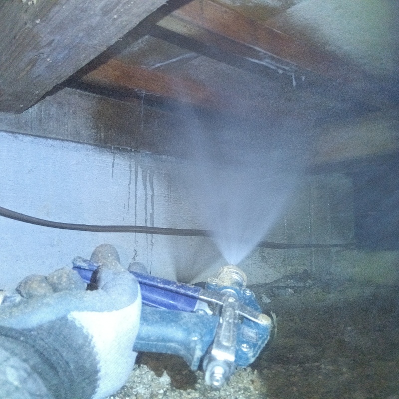 床下木材にシロアリ駆除剤を吹き付ける様子