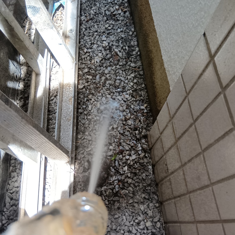 建物まわりの砂利にシロアリ駆除剤を散布
