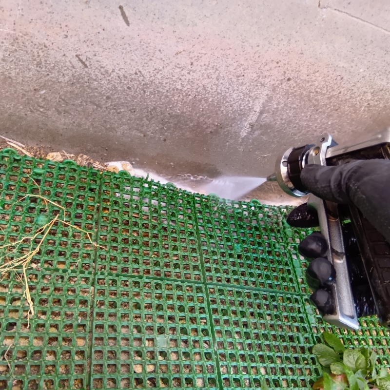 建物周辺に敷いているグリーンマットと壁のすき間にシロアリ駆除剤を散布