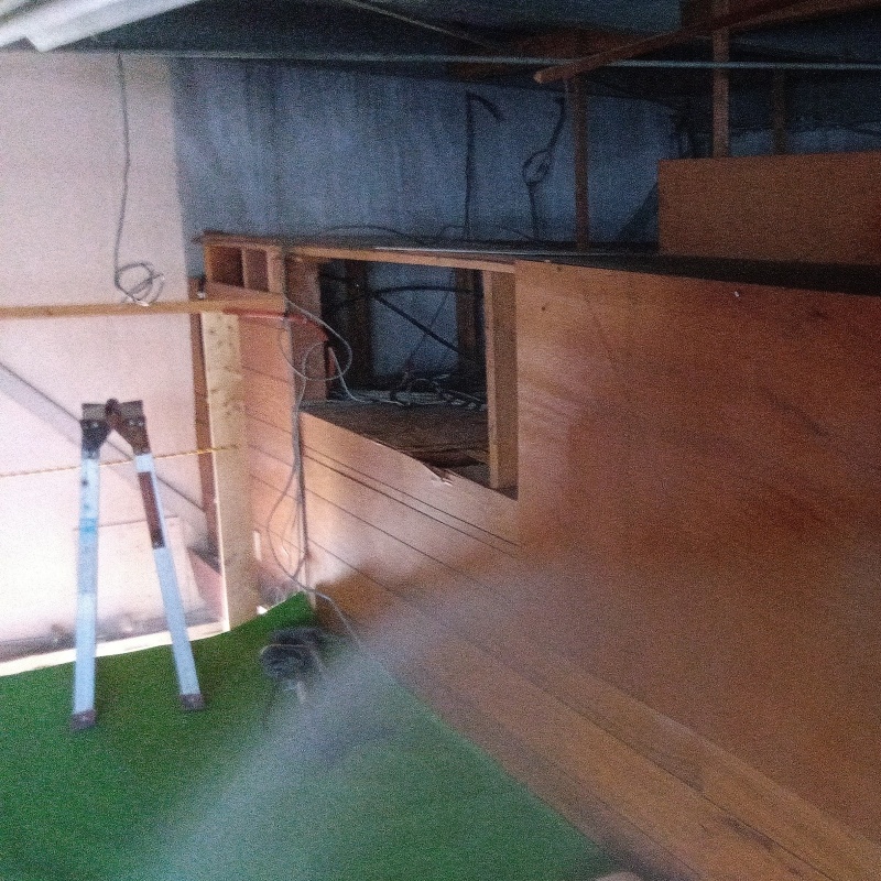 屋根裏の木材にシロアリ駆除剤を吹き付ける様子