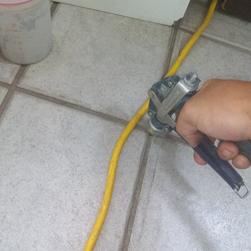 玄関の床にシロアリ駆除を注入する様子