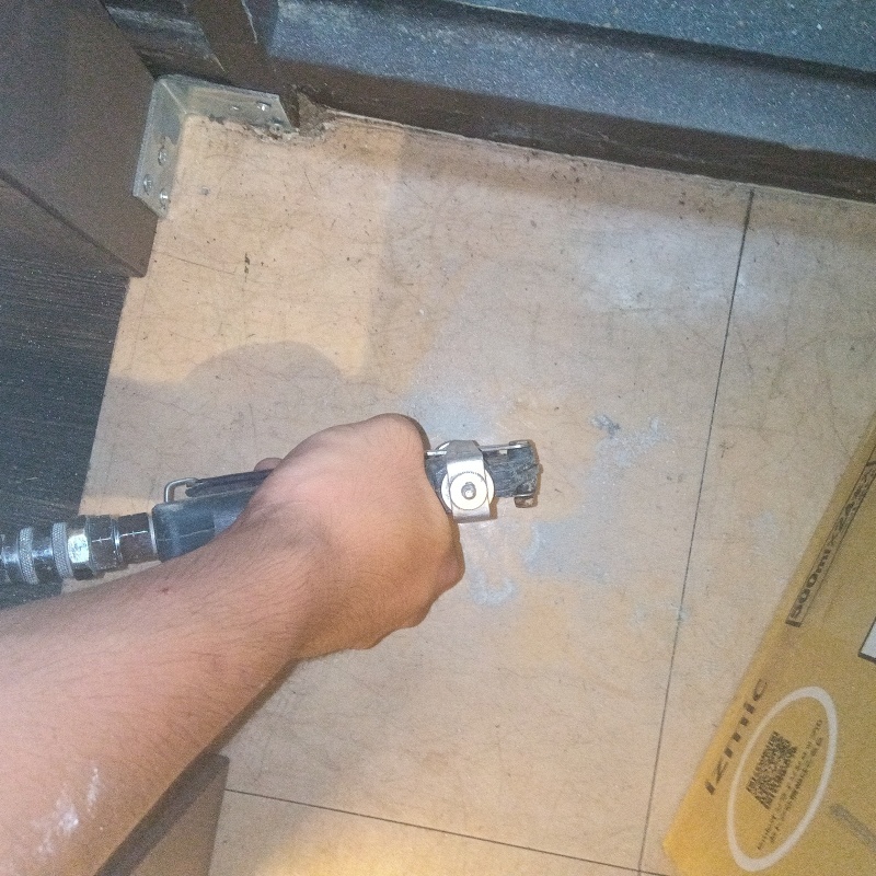 玄関の床にシロアリ駆除を注入する様子