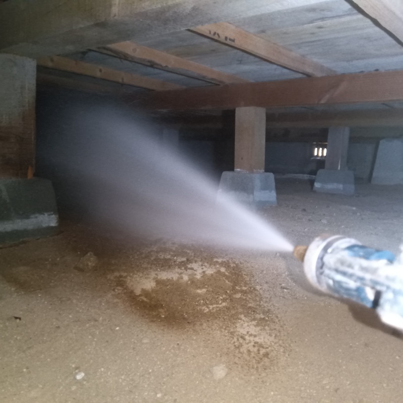 床下の土壌にシロアリ駆除を散布する様子