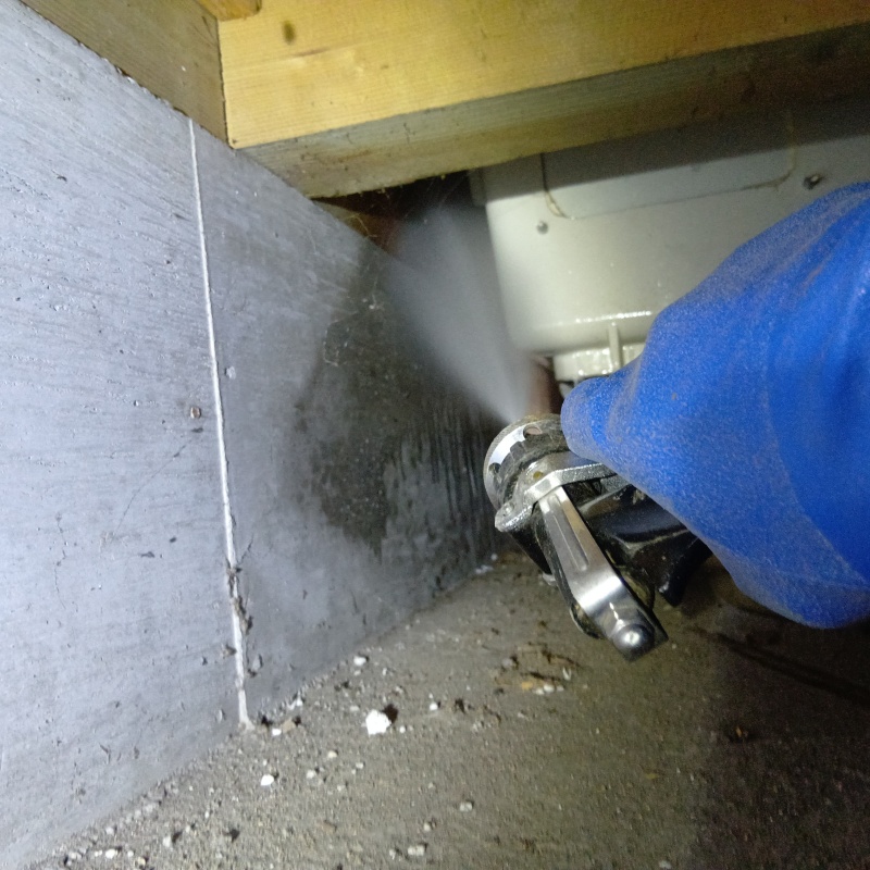 床下の基礎部分にシロアリ駆除を散布する様子