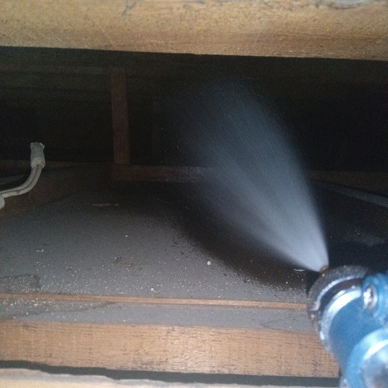 床下の土壌にシロアリ駆除を散布する様子