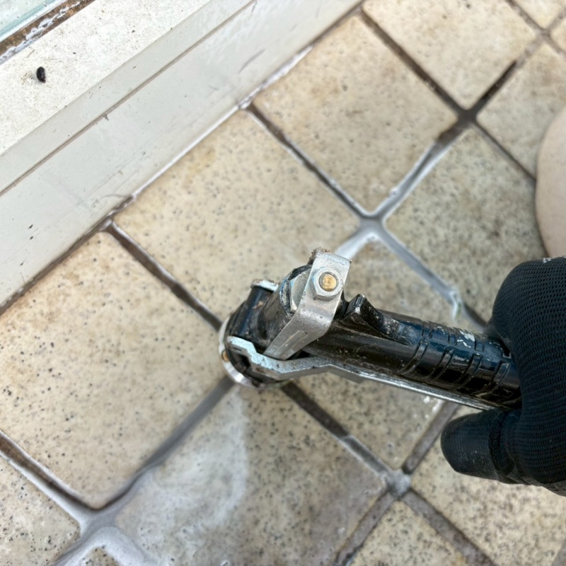 玄関の床にシロアリ駆除剤を注入する様子