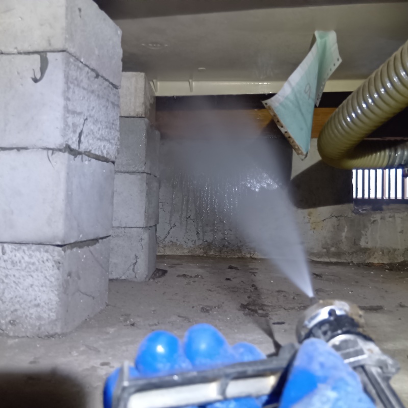 床下の基礎部分にシロアリ駆除剤を散布する様子