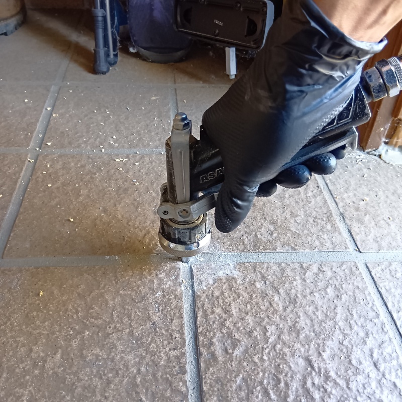 玄関の床にシロアリ駆除剤を注入する様子