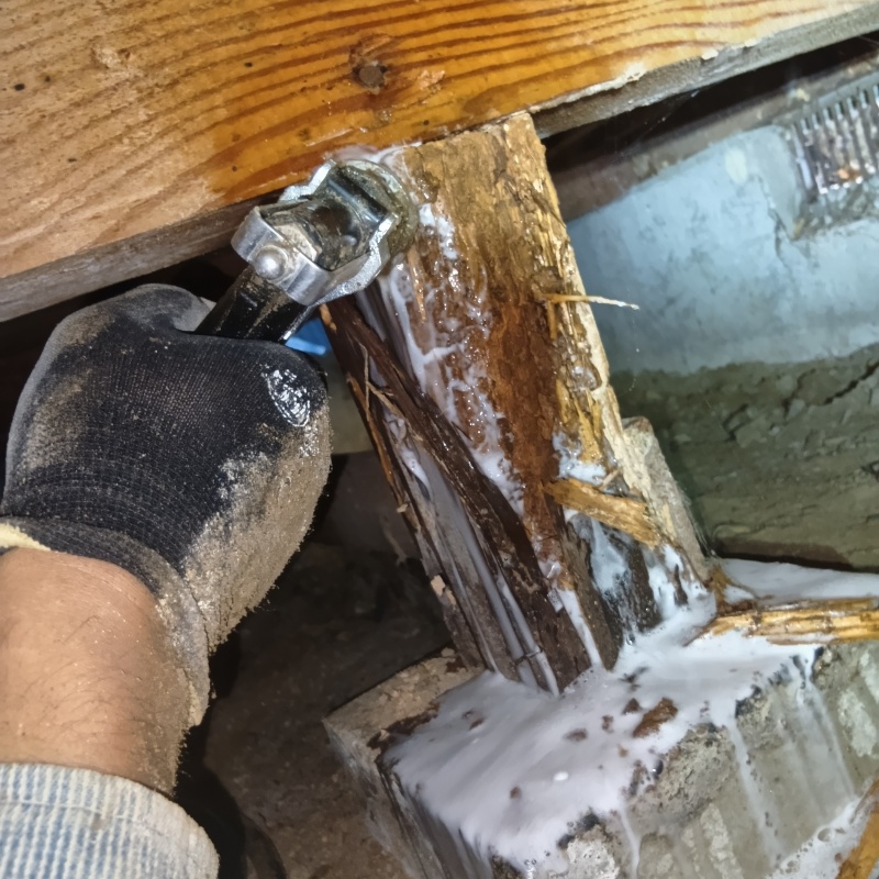 食害を受けた床下の木材にシロアリ駆除剤を散布する様子