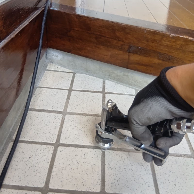 玄関の床にシロアリ駆除剤を注入する様子