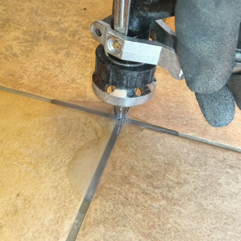 玄関の床にシロアリ駆除剤を注入する様子