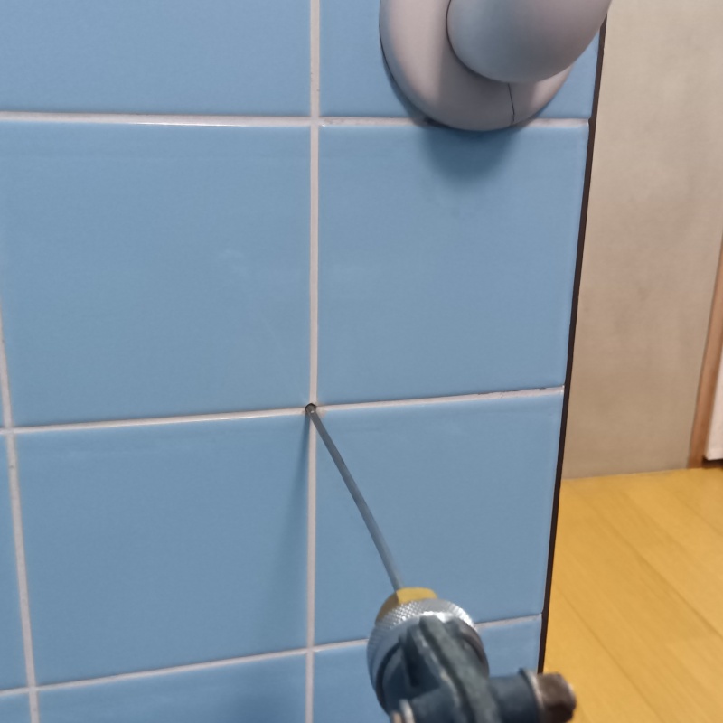 洗面所の壁にシロアリ駆除剤を注入する様子