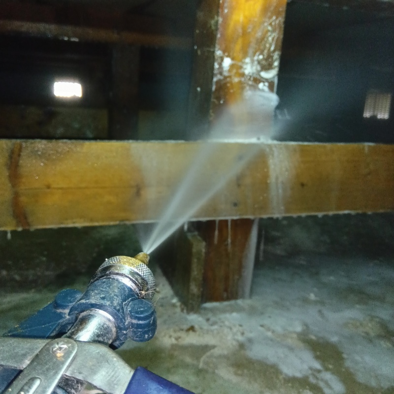 床下の木材にシロアリ駆除剤を散布する様子