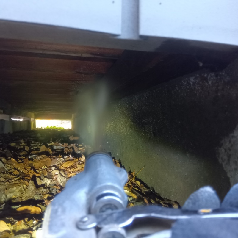 床下の土壌にシロアリ駆除剤を散布する様子