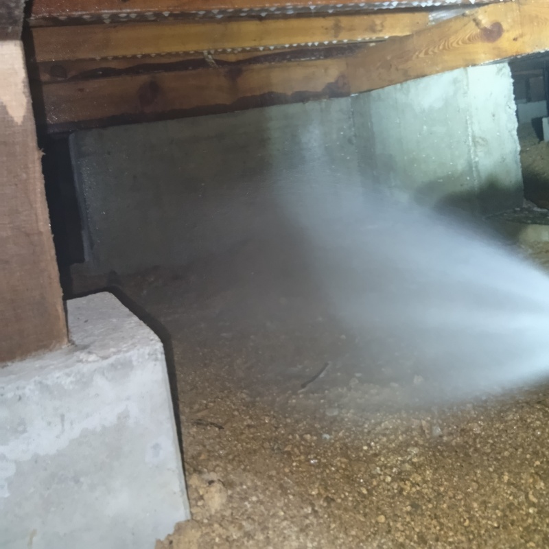 床下の土壌にシロアリ駆除剤を散布する様子