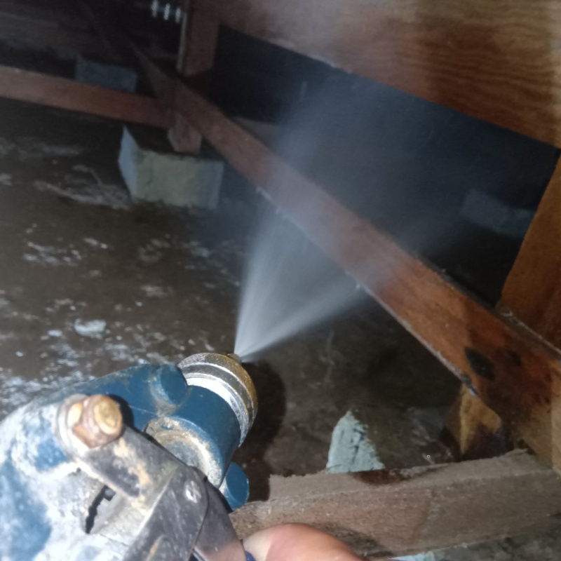 床下の木材にシロアリ駆除剤を散布する様子