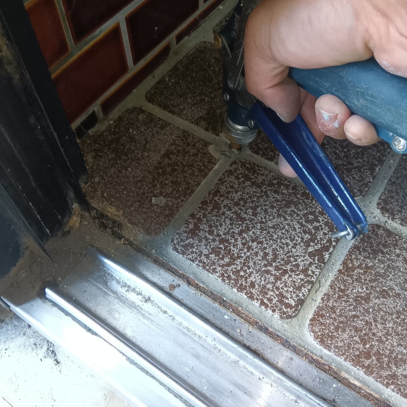 玄関の床にシロアリ駆除剤を注入する様子