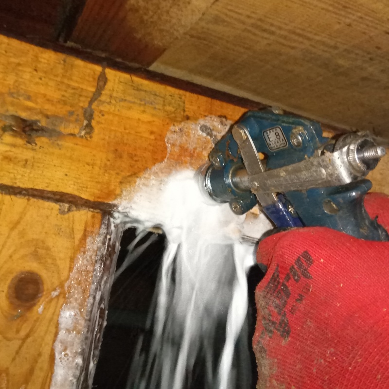 食害を受けた床下の木材にシロアリ駆除剤を散布する様子