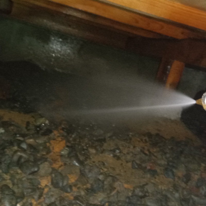 床下の土壌にシロアリ駆除剤を散布する様子